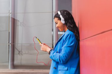 20 'li yaşlardaki genç bir kadın akıllı telefonuyla fotokopi çekiyor. Modern kıyafetler içindeki Afrikalı öğrenci cep telefonuyla sosyal medya kullanıyor..