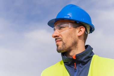 Bir işçi ya da mühendisin portresi, gökyüzüne dik dik bakan, geleceğe bakan, çalışmasıyla gurur duyan. İş kıyafetleri, epi, memnuniyet ve yüksek öğrenim kavramı.