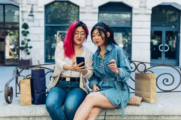 Dos Jóvenes Amigas Asiáticas Sentadas Aire Libre Usando Sus Teléfonos —  Fotos de Stock