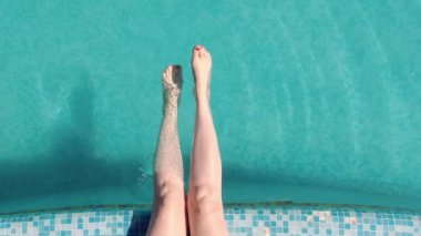 İnce kadın bacakları sıcak bir yaz gününde havuza düşer..