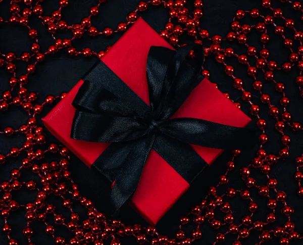黒いリボンとビーズの赤いギフトボックスは黒の背景にあり トップビューの終わりです クリスマスと黒の金曜日のコンセプト — ストック写真