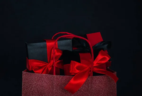 Een Rood Glanzende Tas Met Drie Geschenkdozen Een Zwarte Achtergrond — Stockfoto