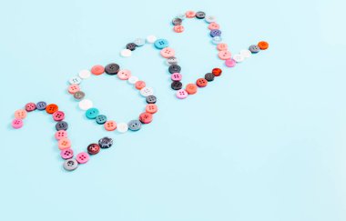 Farklı boyutlardaki çok renkli düğmelerden 2022 numara, köşegen üzerine uzanan açık mavi arkaplan, metin için alan, yakın görünüm. Yeni yıl kavramı.