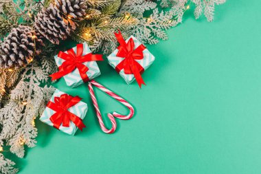 Üç hediye, kalp şeklinde lolipoplar şeker ve solda ladin dalı sağ tarafta fotokopi alanı olan yeşil bir arkaplan, en üstte yakın plan..