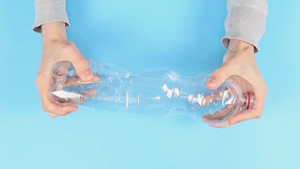 小伙子们的手在蓝色的背景上捏着一个塑料瓶. — 图库视频影像