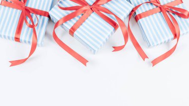 Kırmızı kurdeleli mavi çizgili üç hediye kutusu beyaz bir arka planda, aşağıdan yazı için yer var, yakın çekim üst görünümü var. Noel ve Yeni Yıl kavramı.