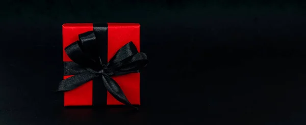 红色礼品盒的左边是一个黑色背景 旁边是一个红色礼品盒 上面有一条黑色缎带 右边是一个特写镜头 圣诞节和黑色星期五的概念 — 图库照片