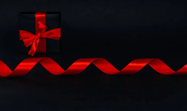 赤いらせん状のリボンとギフトボックスは テキストのためのスペース クローズアップ側のビューと黒の背景の真ん中に位置しています 黒い金曜日 クリスマス 探偵と神秘の概念 — ストック写真