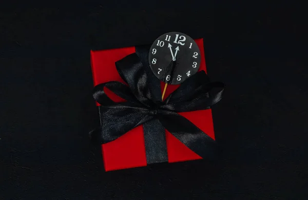 一个红色礼品盒 内附黑色缎带 中间有一个纸钟 黑色背景上有文字空间 顶部有近景 圣诞节和黑色星期五的概念 — 图库照片