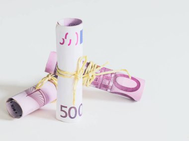 Üç adet 500 avroluk banknot sarılmış ve sol tarafta jüt iplikle bağlanmış, sağ tarafta yazı için yeri olan beyaz bir zemin ile çevrilmiş, yakın plan görünümü var..