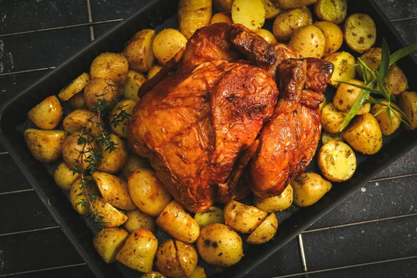 Курица с картошкой в блюде для выпечки на стойке из железной проволоки. — стоковое фото