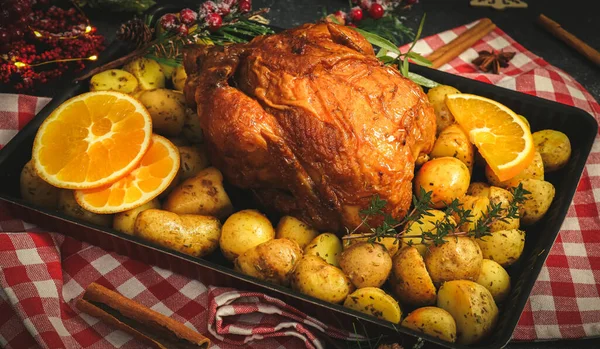 Csirke burgonyával, fűszernövényekkel, narancs és fahéj rudakkal sütőtálban, konyhai szalvétán. — Stock Fotó