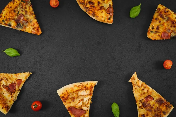 Seis rebanadas de pizza, tomate cherry y hojas de albahaca yacen en un marco forjado sobre un negro —  Fotos de Stock