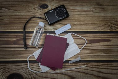 Pasaport, kamera, dezenfektan, tıbbi maske ve koronavirüs testi kahverengi ahşap masa, yakın çekim üst görüş.