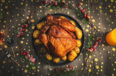 Tabakta patatesli sıcak tavuk ve siyah ahşap bir masada köknar dalları, yıldızlı altın bir masa örtüsü, yakın çekim.