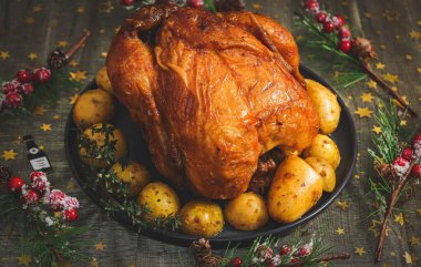 Tabakta patatesli sıcak tavuk ve siyah ahşap bir masa üzerinde köknar dalları ve yıldızlı altın bir masa örtüsü..