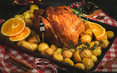 Patatesli tavuk, otlar, portakal ve kağıt saat gece yarısı fırın kabında bir şişe şampanya ve siyah arka planda yeni yıl süslemesi..