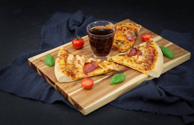 Bir bardak Coca Cola, kesme tahtasında üç dilim pizza. .