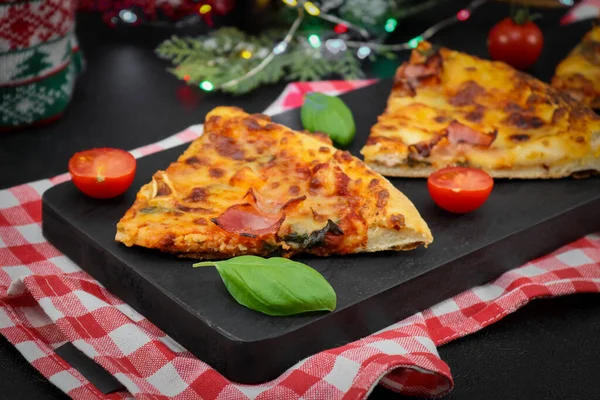 Three slices of pizza, cherry, basil on a black wooden cutting . — Zdjęcie stockowe