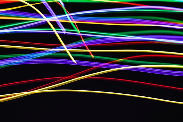 Siyah arka planda mor, mavi, kırmızı ve sarı çizgilerden soyut dondurucu ışık, yakın plan. Astraksiyonu, geçmişi, dokuları kavramsallaştır.