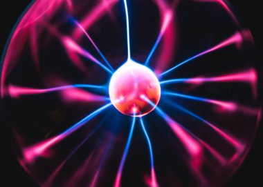 Elektrik yüklü bir gece lambası, ucu dokunaçlı, bulanık ince ipliklerle parıldar. Siyah arka plandaki topun şeklinden yükselen mavi-pembe ışık, yakın plan görüntüsü vardır..