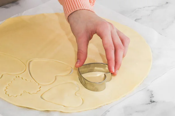 코카서스 지방의 한 십 대 소녀의 손 이 흰 양피지에 금속 쿠키 커터로 짧은 빵 반죽을 자르고 있다. — 스톡 사진