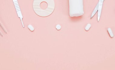 Haplar, tıbbi gereçler, bandaj ve pembe arka planda bir termometre..