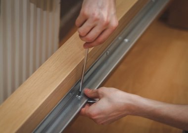 Kafkas bir gencin elleri, metal bir parçayı tahta bir yatağa bağlayan bir tornavidayla vidayı büküyor. Odasında yerde oturuyor, yakından bakıyor. Mobilya montajı kavramı