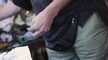 Hands of a caucasian male engraver of the medieval era looking for a tool to work on the desktop in the workshop,side view close-up, slow motion.Artisanal concept,medieval lifestyle.