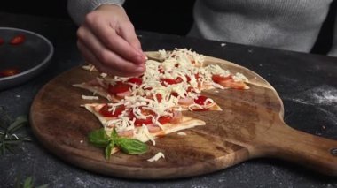 Küçük bir kız noel ağacına mozzarella peyniri serpiyor. Ev yapımı pizza hamuru. Karanlık bir masanın üzerinde. Aile eğlencesi ve yemek yapma konsepti.