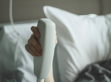 Kafkasyalı genç bir erkeğin eli hastane odasındaki yatağın konumunu değiştirmek için bir düğmeye basıyor. Yatalak hastalar için travma aletleri kavramı, tıbbi ekipmanlar..