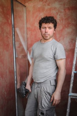 Kahverengi kıvırcık saçlı yakışıklı beyaz adam, inşaat çalışmalarının devam ettiği bir odada, bir iş arkadaşıyla kameranın önünde duygusal olarak iletişim kuruyor. Sigara molası, iletişim kuran insanlar..