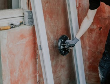 Siyah iş üniformalı beyaz adam cam çerçeveli cam krikoya tutunuyor, kurulum için hazırlanıyor, seçici bir odak ile yakın çekim. Ev yenileme ve pencere montajı kavramı.