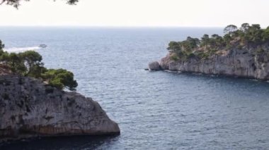 Akdeniz 'de bir geçidi olan iki kayalık dağın güzel panoramik manzarası ve Fransa' nın güneyinde, yan manzaralı, yavaş çekimde yaklaşan ve yakınlaştıran bir tekne..