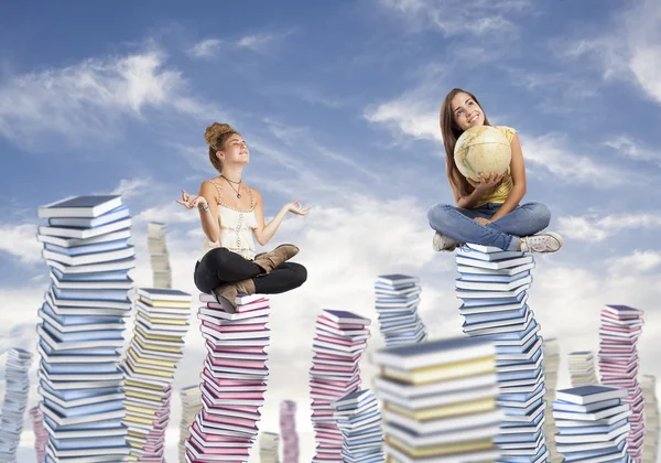 Mulheres sentadas em pilhas de livros — Fotografia de Stock