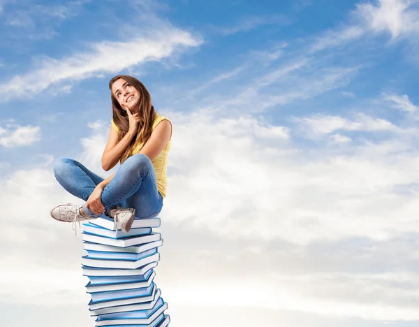 Vrouw die op stapel boeken zit — Stockfoto