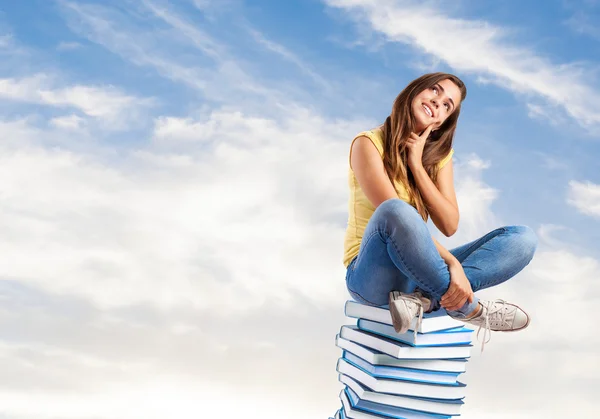 Donna seduta sul mucchio di libri — Foto Stock