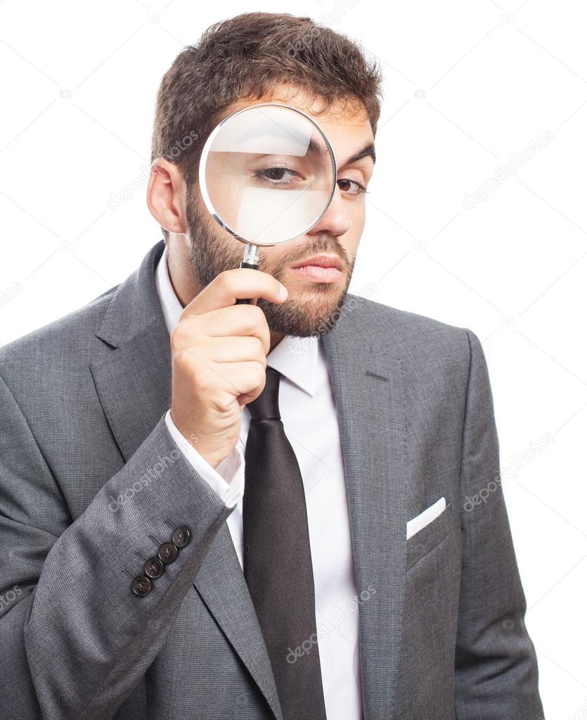 Business man looking through magnifying glass