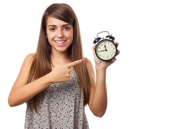 Young woman pointing at alarm clock — Stock Photo, Image