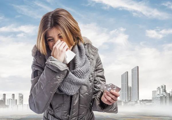 Woman sneezing and holding medicines — Stock Photo, Image