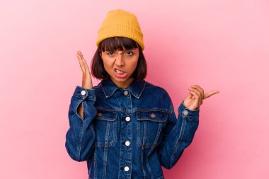 Pembe arka planda izole edilmiş genç melez kadın işaret parmağıyla bir hayal kırıklığı gösteriyor..