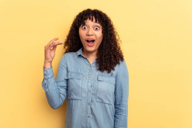 Sarı arka planda izole edilmiş genç bir ırk kadını bir şeye gülüyor, ağızlarını elleriyle kapatıyor..