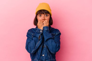 Pembe arka planda izole edilmiş, tırnak yiyen, gergin ve endişeli genç bir ırk..