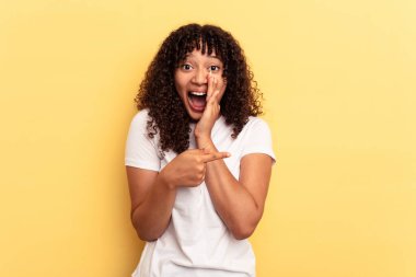 Sarı arka planda izole edilmiş genç melez bir kadın dedikodu yapıyor, bir şeyleri haber veriyor..