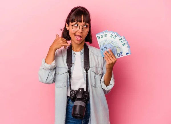 若い混合レース写真家の女性は 指で携帯電話のコールジェスチャーを示すピンクの背景に隔離された法案を保持 — ストック写真