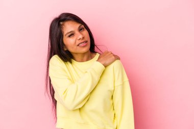 Pembe arka planda izole edilmiş genç Latin kadın omuz ağrısı çekiyor..