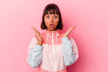 Genç melez kadın pembe arka planda izole edilmiş şaşırmış ve şok olmuş..