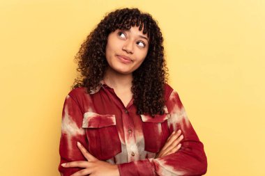 Sarı arka planda izole edilmiş genç melez kadın hedeflerine ve amaçlarına ulaşma hayali kuruyor.