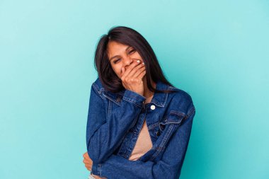 Genç Latin bir kadın mavi arka planda izole edilmiş gülerek, kaygısız, doğal duygular içinde..