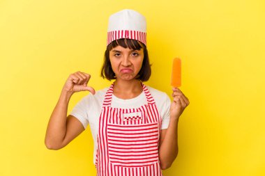 Genç melez dondurma üreticisi kadın sarı arka planda izole edilmiş dondurma tutuyor. Sevimsiz bir jest gösteriyor. Anlaşmazlık konsepti.